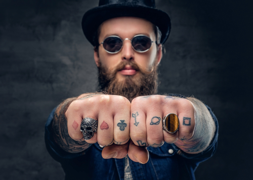 Close up tattooed hipster's fingers with rings
