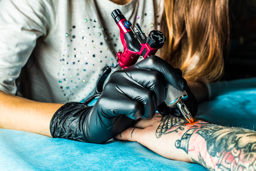 Tattoo artist making a tattoo design on man's arm