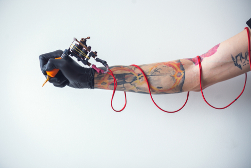 Man's hand holding tattoo machine on white background